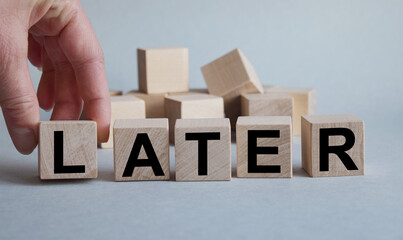 LATER inscription on the texture of wooden cubes. A business man holds a cube in his hand. An inscription on a financial, business or economic theme.