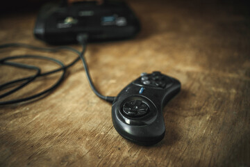 A joystick from an old game console of the 90s. A 16-bit console on a wooden table in the...