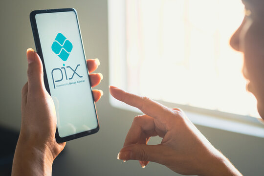 June 26, 2022, Brazil. In this photo illustration, a woman's holds a smartphone with the PIX logo displayed on the screen.