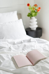 Open book in bed with fresh white linens