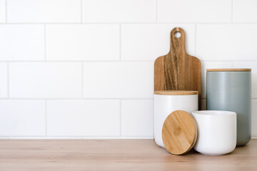 Wooden cutting board and containers on table in kitchen