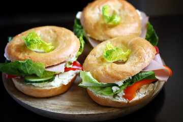 Bagel with vegetables, ham and white cheese.
