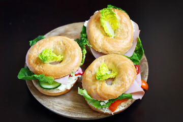 Bagel with vegetables, ham and white cheese.