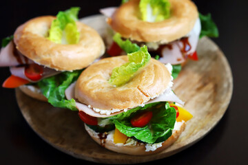 Bagel with vegetables, ham and white cheese.