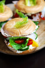 Bagel with vegetables, ham and white cheese.