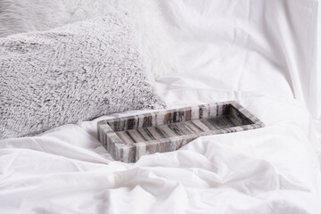 Empty grey marble tray on white bed sheets among fluffy pillows - breakfast in bed