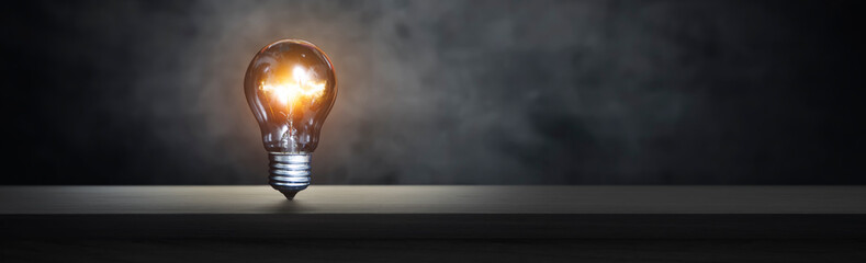 lit light bulb on a wooden table - idea concept