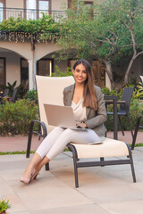 young businesswoman using her laptop in a hotel courtyard