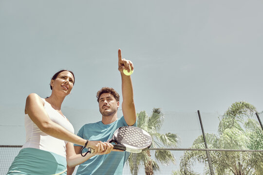 Monitor giving paddle tennis classes to a woman, his student
