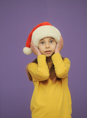 little girl in santa hat on yellow background with a copy space.