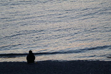 沈む夕日にポツンと1人たたずむ孤独な後ろ姿