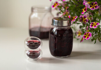 Jars of cherry jam. Pink flowers next to a jar of jam