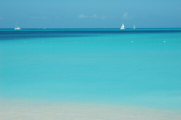 sailboats in the distance of an expanse of calm Caribbean ocean.