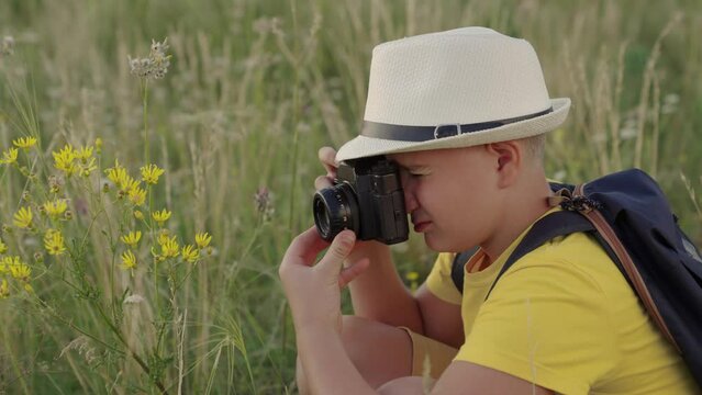 Child boy plays with camera, photography flowers in summer park, Child dreams of traveling making discoveries. Happy boy, child dreams of becoming photographer. Concept of children's fantasy in nature