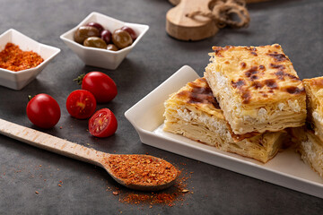 Water pastry on the plate. Composition of water pastry, tomato, hot pepper and olives on old wooden table.