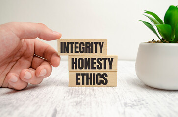 INTEGRITY, HONESTY, ETHICS words on wooden blocks and hand