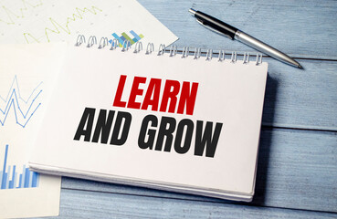 Learn and grow text on notepad on wooden background and charts