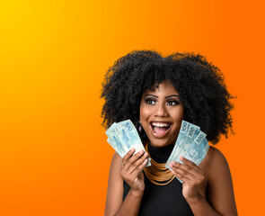 woman holding money, young smiling woman holding Brazilian money, orange gradient background