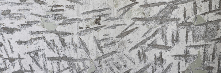 Texture of old concrete wall. Rough gray surface of concrete with a chaotic pattern of potholes and scratches. Wide panoramic background for design.
