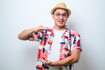 Asian man gesturing with hands showing big and large size sign, measure symbol. smiling looking at the camera. measuring concept.