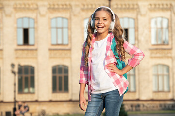 Fototapeta premium Happy teen girl listening to music in school yard outdoors, copy space