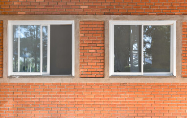 Two windows on brick wall, outdoor view. Window from front outside of house.