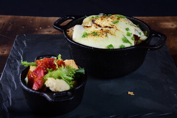 pan with meatballs rice cheese and salad, in iron pan on slate stone