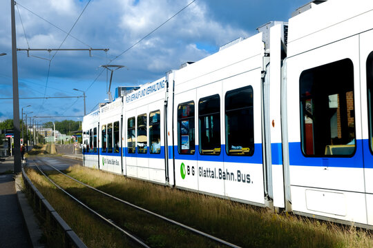 "Zurich, Switzerland- Circa June, 2022: Selective focus picture with noise effect and motion blur part of moving VBG Tram on grass tramway."