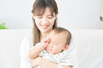 Fototapeta na wymiar リビングで赤ちゃんを抱っこする母親