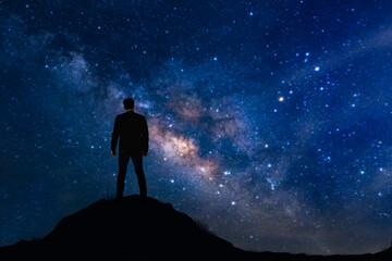 Silhouette of businessman on mountain with starry night sky background. Business success and leadership concept.