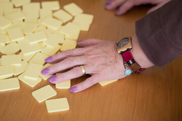 Hand of a senior woman mixing the tiles of a game of Rummy