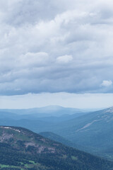 Gentle hills in gray haze on horizon. Rock ridge under sunset sky. Clouds gathered on mountain valley. Mystery of Future Weather Uncertainty