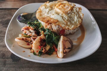 Thai Rice topped with stir-fried squid and basil with fried egg.