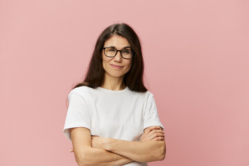 Fototapeta premium portrait of a cute, attractive brunette in a white tank top on a pink background, with a pleasant smile, standing in glasses for vision