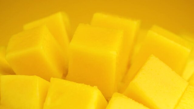 Macro shot Slice mango cubes rotating against Yellow background, Tropical Fruit