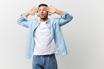 Excited shocked happy tanned handsome man in casual basic t-shirt headphones hold palms up listen cool music posing isolated on over white studio background. Copy space Banner Mockup. Playlist concept
