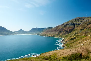 Fototapeten Panoramic view of the ocean surrounded by mountains from a hiking trail in Hout Bay, Cape Town in South Africa. Popular tourist attraction of hills and calm water against a blue sky with copyspace © SteenoWac/peopleimages.com