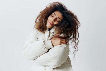 Happy Smiling Curly Pretty Latin Woman Hugging Herself Enjoyed Beige Warm Coat Closing Eyes Posing...