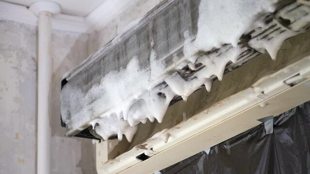 A man sprays special foam to clean air conditioners on the radiator. Split system maintenance.