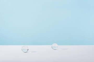Acrylic glass spheres on blue background for cosmetic or perfume showcase. Creative geometric...
