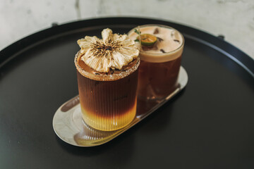 Two iced yusu orange coffee special drinks served on black table in the cafe.