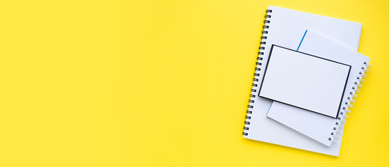 A stack of blocks and notebooks with a spiral. Bright yellow background. Banner. copyspace. Top view, flat lay. Back to school concept.