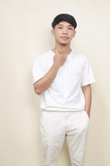 Portrait of standing asian young man wearing white t-shirt and white pants on isolated background