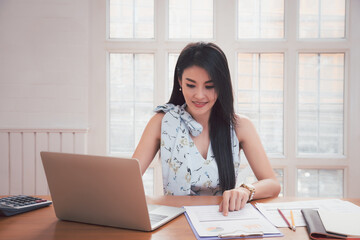 Young asian woman in smart casual wear working with laptop in home office.