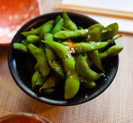 Delicious vegetarian garnish of green soybeans on black bowl