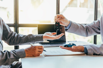 Closeup hand giving a car key and sign contract for loan credit financial, lease and rental concept.