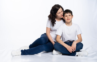 Fototapeta na wymiar mother with son in jeans and white t-shirts on a white background. motherhood concept