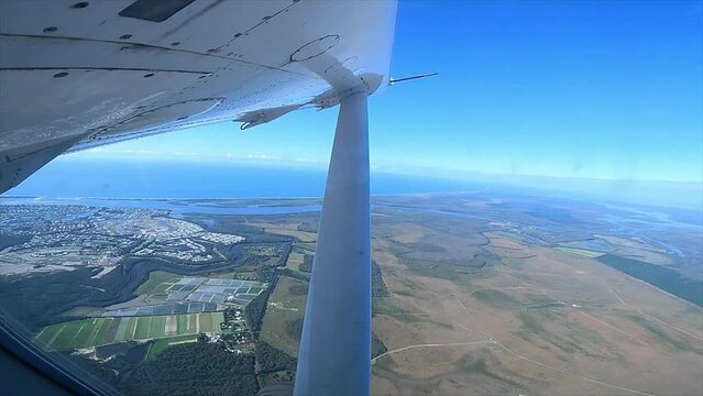 The view through the window of a light aircraft as it ascends over the coastline