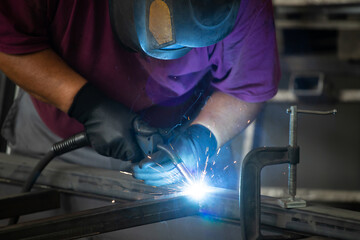 Industry worker welding iron pieces at work