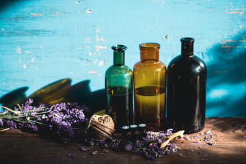 Bottle with aroma oil and lavender flowers on blue background